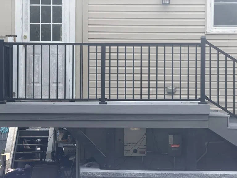 Black aluminum railing detail against house siding at top of deck stairs