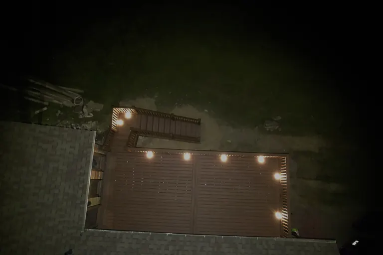 Night aerial of finished rectangular deck with string/post lighting outlining the perimeter