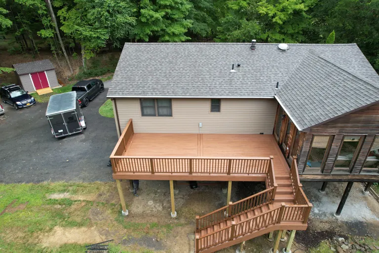 Aerial daytime view of an elevated rear deck with staircase to grade
