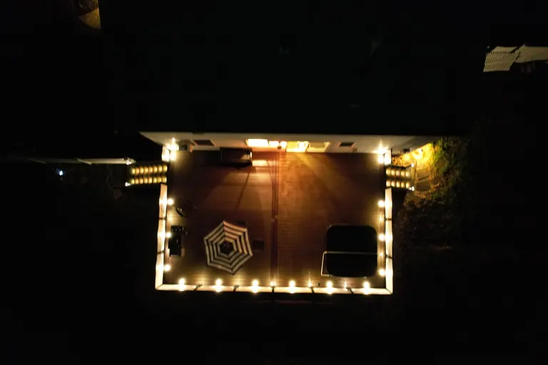 Night aerial of deck with market umbrella and built-in perimeter lighting