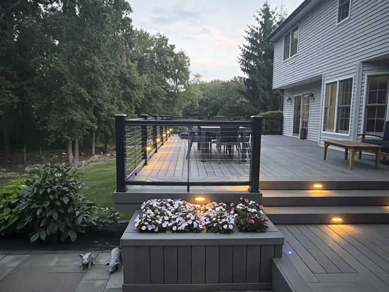 Twilight deck view down toward dining table with cable railing step lighting