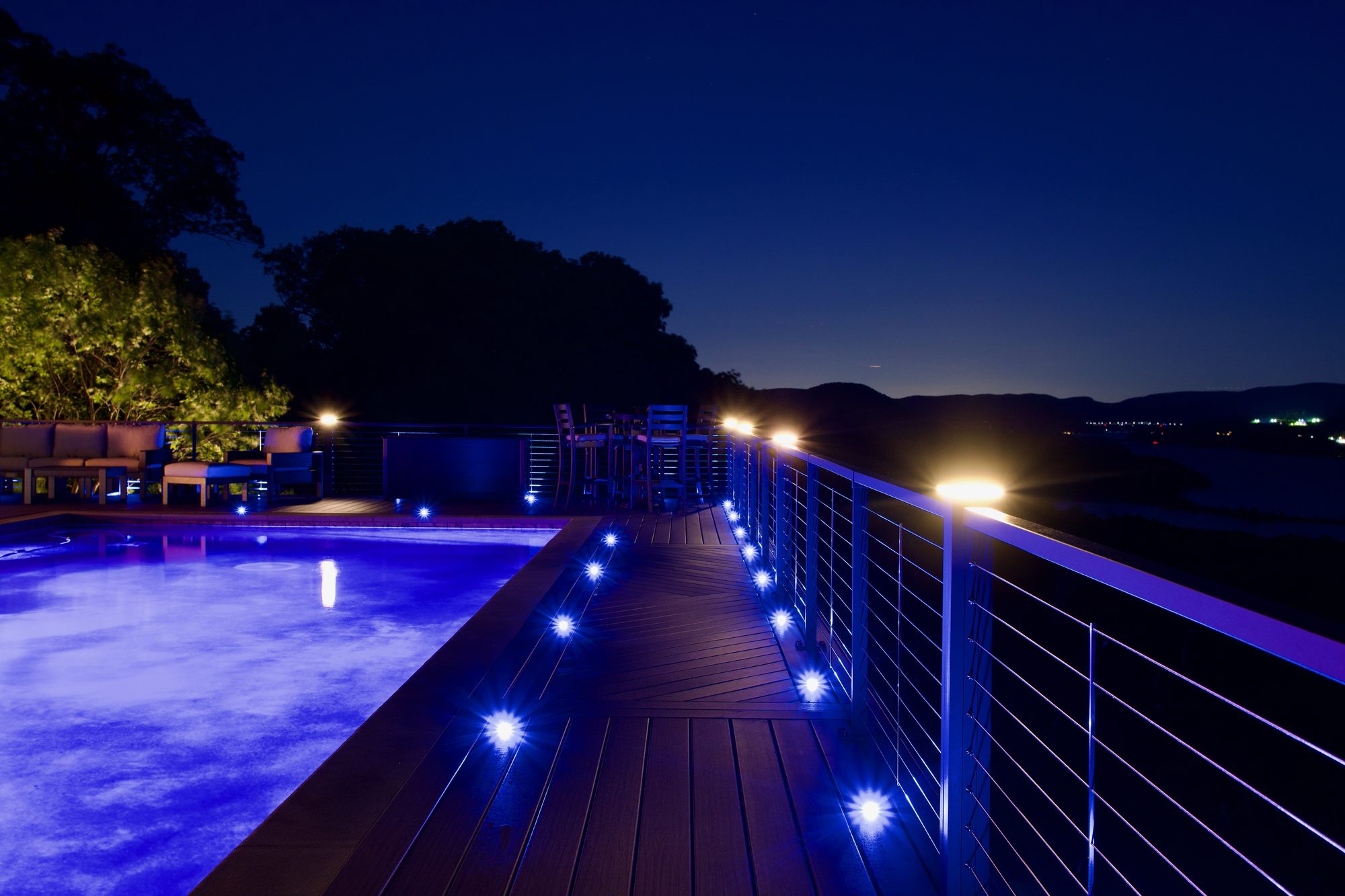 Trex deck with aluminum cable railing at sunset and blue integrated LED deck lighting — Pinnacle Decking Hudson Valley NY