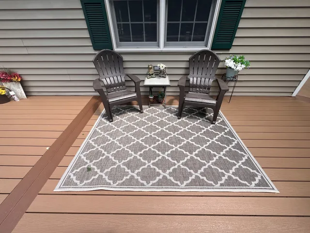 Two Adirondack chairs on a composite porch with an outdoor rug
