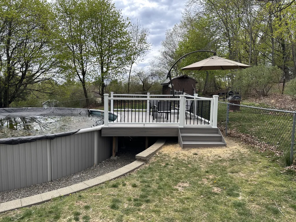 Composite deck over an above-ground pool with a curved concrete walkway underneath, Dutchess County, NY
