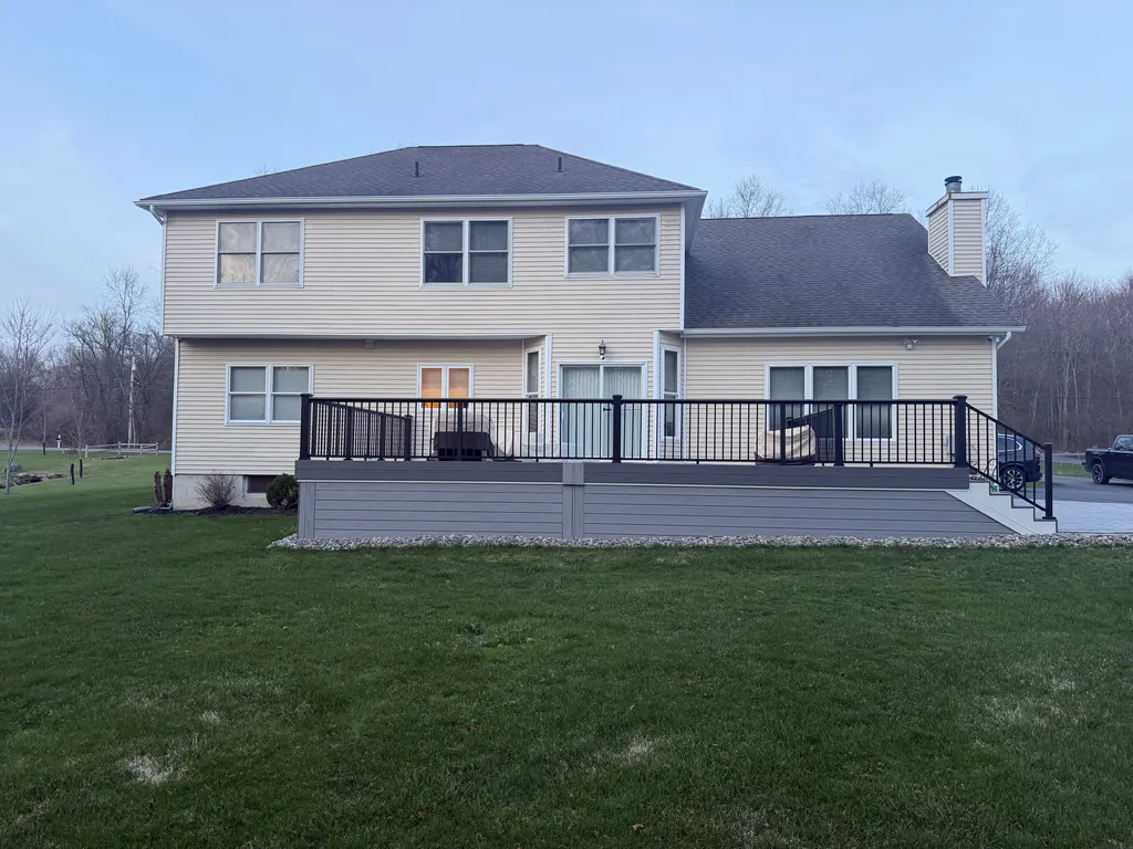 Finished deck with black railing at dusk, rear elevation of the home, Orange County, NY