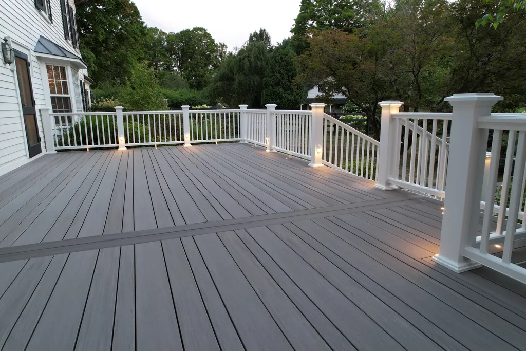 Wide view of the same grey-tone composite deck with white railing at dusk, post-cap lights on, Dutchess County, NY