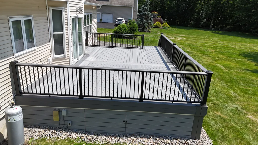 Gray composite deck with black aluminum railing along a lawn
