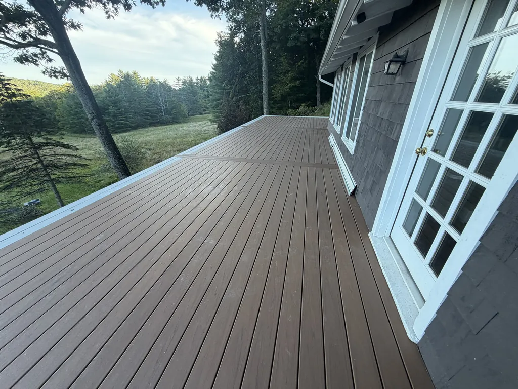 New Trex deck along a shingled house with a breaker board and picture-frame border, decking complete before railings, Boiceville