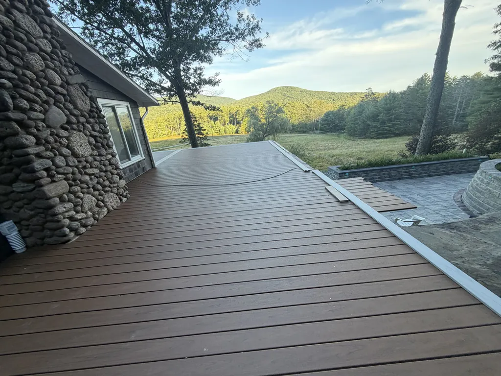 New Trex deck with a contrasting picture-frame border, decking complete before railings, looking out over a Catskills meadow in Boiceville