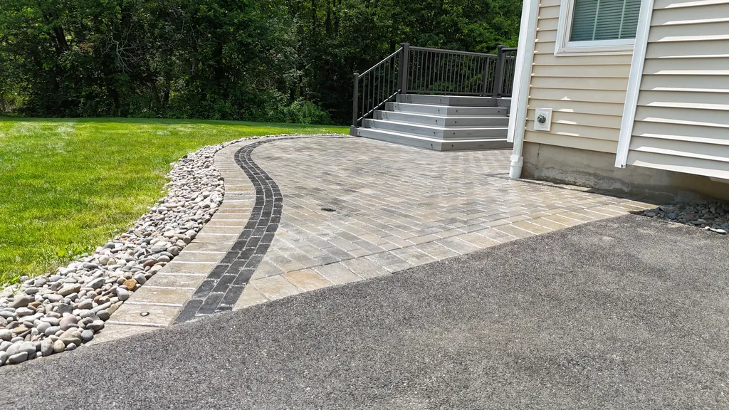 Paver walkway and steps leading up to a deck, tree line behind, Orange County, NY