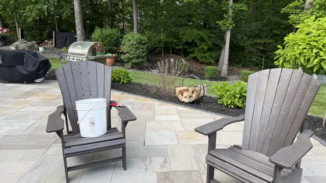 Stone patio with Adirondack chairs beside a garden