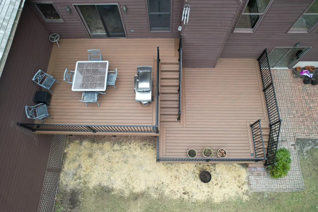 Two-level brown composite deck with black railing and stairs between levels, brick patio below, Dutchess County, NY