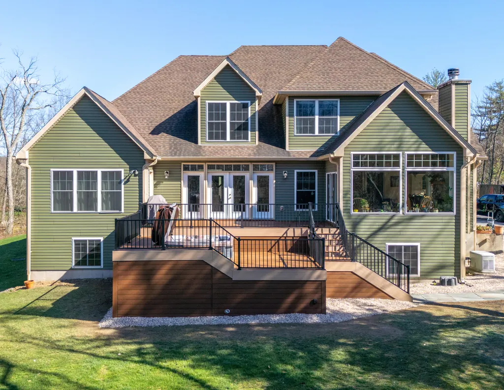 Two-tier deck with black railing across the back of a green house