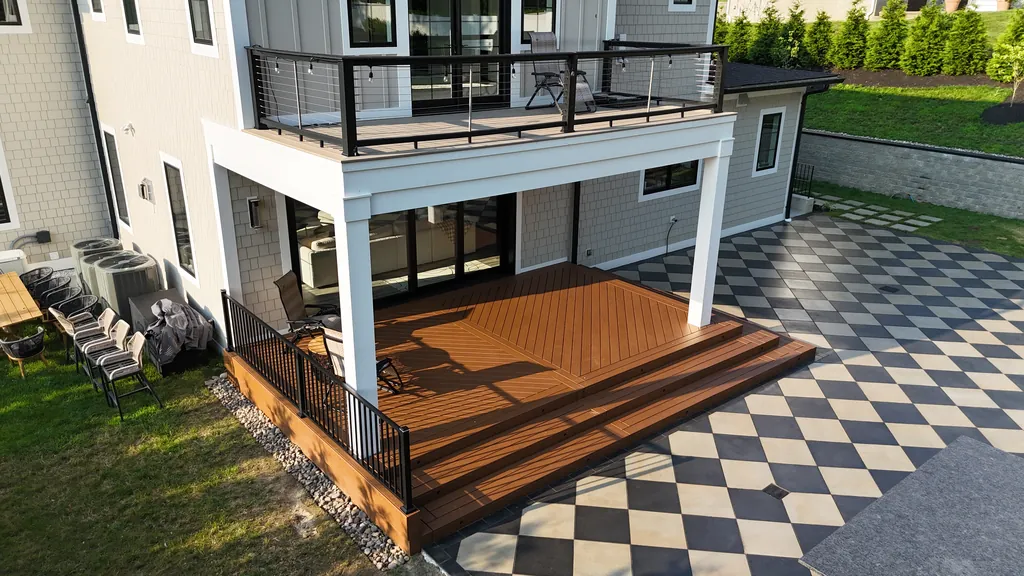 Under-deck view with white pergola posts, black rail, and screened AC condensers above a checkerboard patio, Westchester County, NY